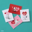 Four Peanuts-themed Valentine's Day cards on a teal surface, featuring Snoopy, Charlie Brown, Lucy, and Schroeder with red and pink hearts and cheerful messages like "You're Just My Type!" and "You Rock!.