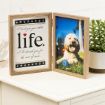 A double photo frame on a white table. One side has a message with a red heart that reads, “I loved you your whole life. I’ll cherish you for the rest of mine.” The other side shows a happy dog sitting on grass with a blue ball.