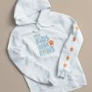 A white hoodie with the phrase "my KIDS HAVE PAWS" and orange paw prints on the chest and right sleeve, displayed on a beige surface.