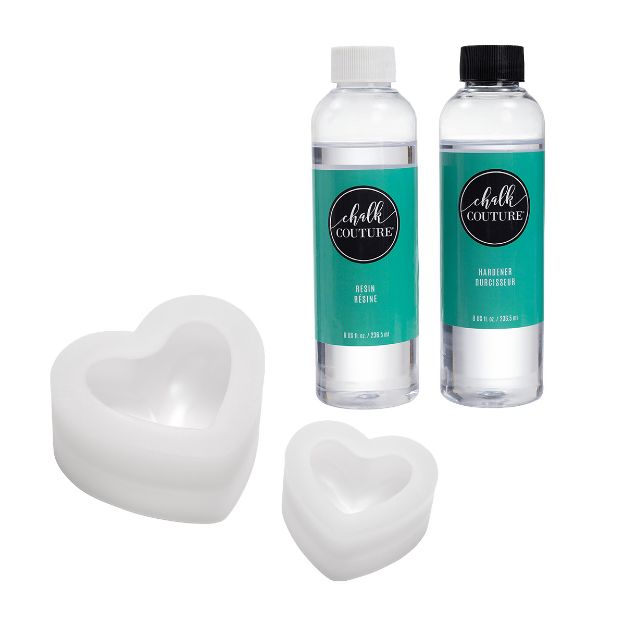 Two bottles labeled "Chalk Couture" resin and hardener stand upright beside two white, heart-shaped silicone molds of different sizes on a plain white background.