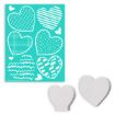 A teal stencil sheet with six heart shapes, each featuring different white patterns, is shown next to two small, white, wooden heart-shaped cutouts.