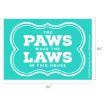 A teal sign with white text reads, "The PAWS make the LAWS in this house." The dimensions are 6½ inches wide and 4½ inches tall.