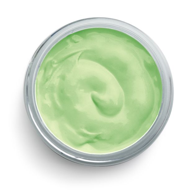 A small, round, clear container filled with smooth, light green cream viewed from above on a white background.