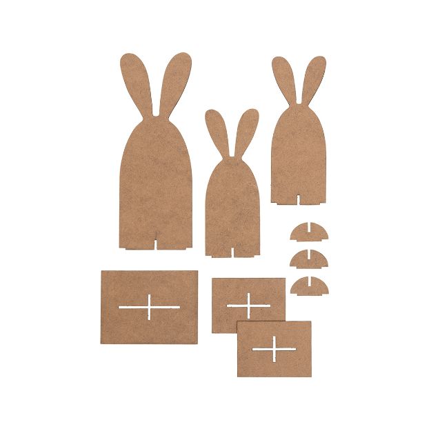Laser-cut brown MDF pieces shaped like bunnies, rectangular bases, and small semi-circles, arranged on a white background for assembly into standing bunny figures.