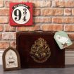 A decorative Harry Potter-themed display featuring a Platform 9 3/4 sign, a suitcase with the Hogwarts crest, a framed Hogwarts emblem, and a tag with Hedwig the owl, all set against a brick wall.