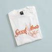 A folded white t-shirt with an orange line drawing of a cartoon rabbit and the words "Good Vibes" printed on the front.