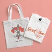 White tote bag and white t-shirt, both featuring Bugs Bunny designs, placed on a pink background. The bag says "Bugs Bunny" and the shirt says "Good Vibes" with Bugs Bunny’s face.