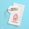 A white napkin with a floral Easter egg design featuring Snoopy hugging Woodstock, and "Happy Easter!" text. Next to it is a gift tag with "Happy Easter" decorated with colorful eggs and Snoopy holding a flower.