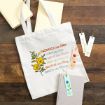 A white tote bag with floral designs and colorful text that reads: "Sacrifice like Esther, Love like Ruth, Serve like Martha, Pray like Hannah, Believe like Mary, Dance like Miriam," next to books and floral bookmarks.