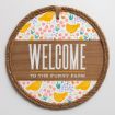 Round sign with rope border that reads "WELCOME TO THE FUNNY FARM." The background has a floral pattern with yellow chickens, orange chicks, and colorful flowers on a white backdrop.