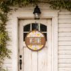 A round sign hangs on a white wooden door under a lantern, reading "WELCOME TO THE FUNNY FARM" with colorful patterns and leafy vines framing the doorway.