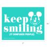 A turquoise sign with white text that says "keep smiling (it confuses people)" and features a smiling Mickey Mouse face. The sign measures 11 inches wide by 8.5 inches tall.