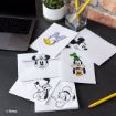 Envelopes and stationery featuring Disney characters—Minnie Mouse, Mickey Mouse, Daisy Duck, Goofy, and Pluto—are spread on a desk near a laptop, a plant, a glass pencil holder, and two yellow pencils.