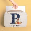 A hand slides a laptop into a beige bag featuring a large navy "P" with stars and moons, and an illustration of Winnie the Pooh holding a honey pot. Text below reads "is for Pooh.