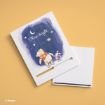 Two white notebooks on a yellow surface; one features Winnie the Pooh and Piglet holding hands, looking at the night sky with stars and the words “Shine bright.” The other notebook is plain with a black elastic band.