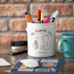 A white pen holder with Winnie the Pooh and Piglet illustration and the words "My favourite story is with you," sits on a desk with colorful pens, a stapler, a blue mug, a mouse, and a mousepad.