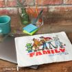 A laptop partially in a white Disney/Pixar pouch with Toy Story characters and "FAMILY sticks together" printed on it. The scene includes a green cup, pens, sticky notes, paper clips, and a glass vase on a wooden desk.