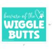A teal sign reads “beware of the WIGGLE BUTTS” in white letters, with a heart and paw print graphic. The dimensions shown are 11 inches wide by 8.5 inches tall.