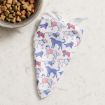 A white dog bandana with red and blue cartoon dog illustrations lies on a light stone countertop next to a metal bowl filled with multicolored dry dog food.