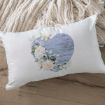 A white rectangular pillow with a heart-shaped design featuring blue wood texture, white flowers, and butterflies, placed on a wooden floor next to a chunky cream knit blanket.
