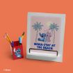 A white tablet stand with a "Lilo & Stitch" design shows Stitch and Angel under palm trees with the words "NAMA-STAY AT THE BEACH." Next to it is a red pencil holder with an image of Stitch, against an orange background.
