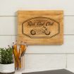 A wooden sign on a white wall reads "A Family Co. Rad Dad Club" with an illustration of Snoopy sitting on a motorcycle. Below, there’s a cup holding pencils and a small potted plant.