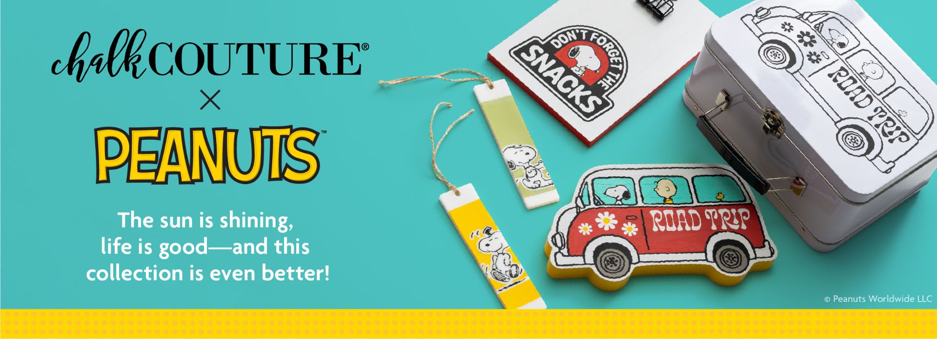 A Chalk Couture x Peanuts collection display with Peanuts-themed crafts, including a decorated lunchbox, “ROAD TRIP” sign, bookmarks, and a cookie shaped like a van, with Snoopy and Woodstock designs on a turquoise background.