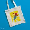 White tote bag with an illustration of Superman flying against a yellow background, set on a bright blue surface. Superman is depicted with a red cape, blue suit, and fist forward in a dynamic pose.