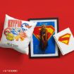 A white pillow with Krypto and Superman designs, a framed Supergirl print, and a spiral notebook with a Superman logo are arranged on a bright red background.