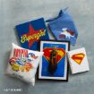 A collection of Supergirl and Krypto-themed merchandise, including a blue and red "Supergirl" sign, a blue bandana with Krypto, a pillow, framed Supergirl art, a Krypto notepad, and a notebook with the Supergirl logo.