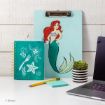 A desk with a teal clipboard featuring Ariel from The Little Mermaid, a matching notebook with white sea-themed designs, a pencil, sticky notes, a striped succulent pot, and part of a laptop.