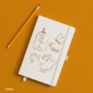 A white notebook with brown line drawings of a rose in a glass dome, two books, Mrs. Potts, and Chip from Disney's "Beauty and the Beast" lies next to a yellow pencil on an orange background.