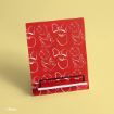 A red book or tablet stand with white illustrations of bows, apples, birds, and clouds on a yellow background. The bottom features a black holder to keep the book or device in place. Disney copyright is visible in the corner.