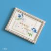 A decorative frame with pearl accents displays an illustration of two bluebirds, flowers, and butterflies, surrounding the gold text “happily, forever” on a light background. Disney logo is in the lower-left corner.