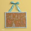 A corkboard with pastel sketches of Disney princess themes, including castles, shoes, and names like Belle and Rapunzel, in a blue ornate frame hanging from a blue ribbon against a yellow background.