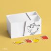 A white desk organizer with an illustration of Mrs. Potts from Disney's Beauty and the Beast, holding notepads and pens. Four book-shaped keychains in red and yellow lie in front on a yellow surface.