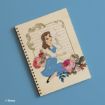 A spiral notebook with an illustration of Belle from Disney's Beauty and the Beast, sitting among colorful roses, holding a dandelion, with elegant script in the background on a wooden-style cover.