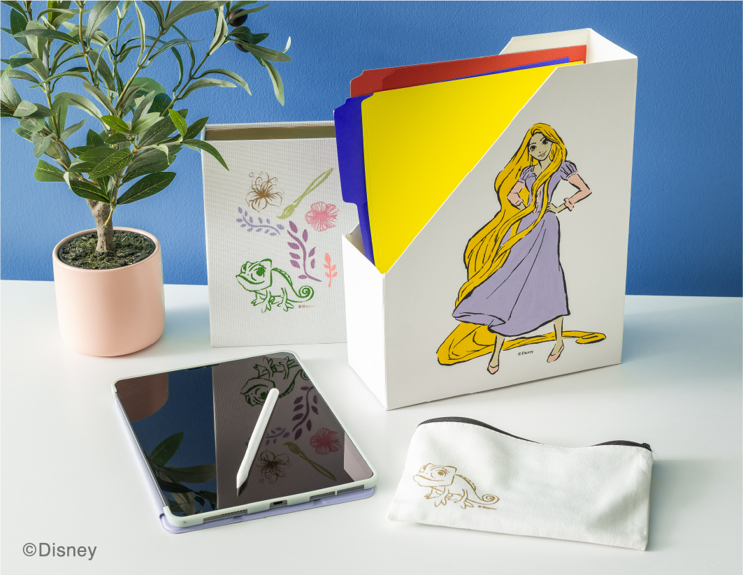 A white file organizer with Disney's Rapunzel illustration holds colorful folders on a desk with a potted plant, a tablet with a stylus, and a white pencil case with a chameleon embroidery. ©Disney.