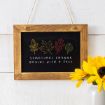 A wooden-framed chalkboard hangs on a white wall, displaying colorful leaf drawings and the words “Sometimes change begins with a fall.” A jar with yellow sunflowers sits in the bottom right corner.