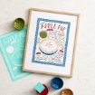 Framed illustrated apple pie recipe print on a marble surface, with a teal unframed version beside it and open paint jars in red, green, and gold nearby. The print features a pie drawing and handwritten instructions.