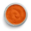 A glass bowl filled with smooth, orange-colored sauce or dip, viewed from above against a white background.