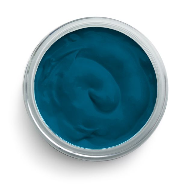 A jar filled with smooth, creamy, dark teal-colored paint or cosmetic cream, viewed from above against a white background.