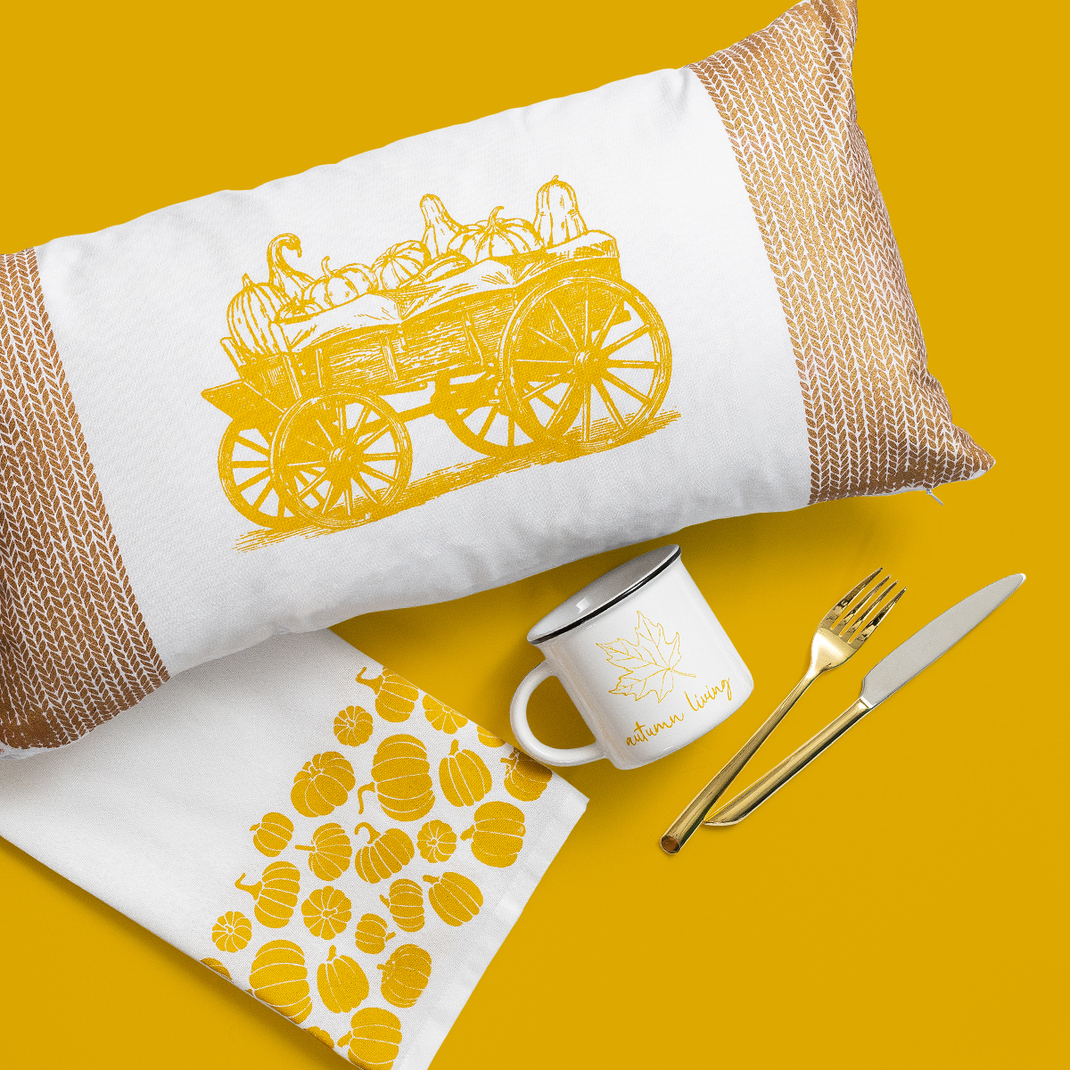 A white pillow with a yellow wagon and pumpkin design, a white mug with "autumn living" and a leaf, a white towel with yellow pumpkins, and gold-colored fork and knife, all on a yellow background.