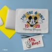 Laptop sleeve with Mickey Mouse image, text "The One & Only 1928 Mickey Mouse," and a small pouch with "Oh Boy!" in red text with Mickey ears, on a blue desk with a laptop and yellow folder.