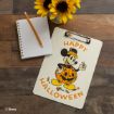 A clipboard with “Happy Halloween” and Mickey Mouse in a pumpkin costume, beside a notepad with a pencil and a vase of sunflowers on a wooden table.