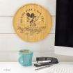 A round wooden plaque with Mickey Mouse raking leaves, captioned “Turning Over a New Leaf.” It’s displayed above a desk with a teal coffee mug, stapler, pen, and part of a computer monitor.