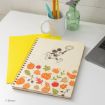 A spiral notebook with Mickey Mouse and fall-themed illustrations, a yellow folder, pencils in a white mug, a green glass vase with flowers, and part of a laptop on a white desk.