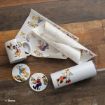 Disney mugs, coasters, and a tumbler decorated with cartoon characters holding autumn leaves, plus matching patterned wrapping paper, all displayed on a rustic wooden surface.