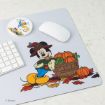 A mouse pad with Mickey Mouse in autumn clothes beside a basket of pumpkins, surrounded by fall leaves. Nearby are a keyboard, a white mouse, and a round Donald Duck coaster.