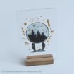 A clear card on a wooden stand features black and gold illustrations: Hogwarts castle in a crystal ball, lightning bolts, stars, Harry Potter’s glasses, a candle, and the word “Hogwarts.” Copyright and publishing info is at the bottom.